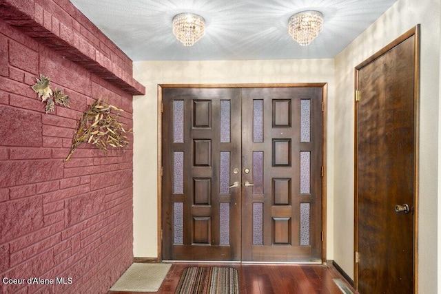entrance foyer featuring baseboards, wood finished floors, and a chandelier