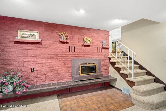 stairs featuring visible vents, a glass covered fireplace, and tile patterned floors