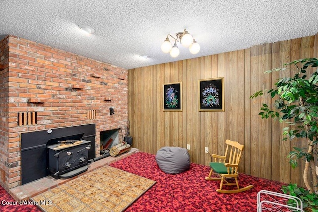 interior space with wooden walls, carpet, a wood stove, and a textured ceiling