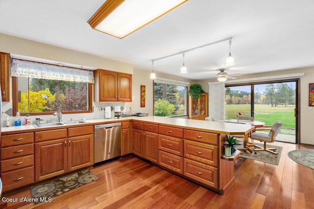 kitchen featuring a sink, light countertops, stainless steel dishwasher, and a peninsula
