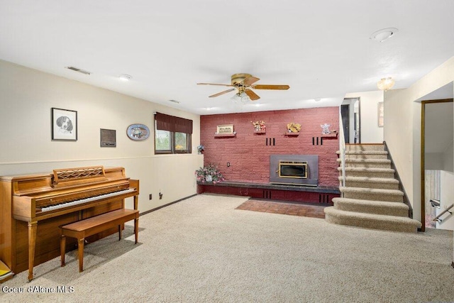 carpeted living area featuring a glass covered fireplace, a ceiling fan, stairs, and visible vents