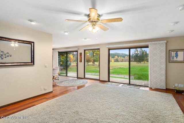 doorway to outside featuring a ceiling fan, baseboards, and wood finished floors