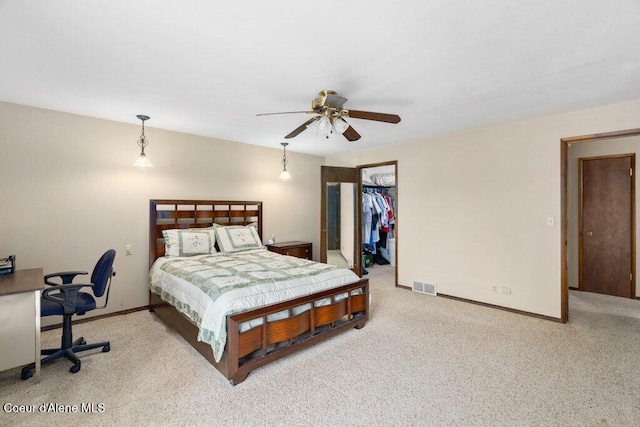 carpeted bedroom with ceiling fan, visible vents, baseboards, a closet, and a spacious closet