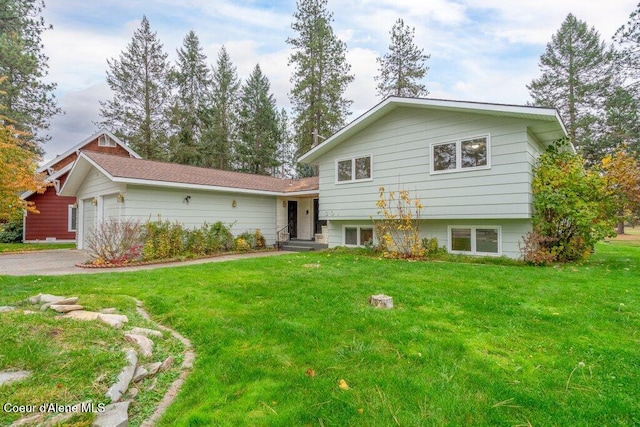 tri-level home featuring an attached garage, driveway, and a front yard