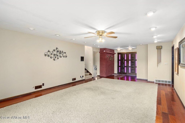 spare room featuring ceiling fan, dark wood finished floors, stairs, baseboards, and visible vents
