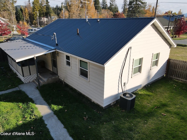 rear view of house featuring a lawn and central air condition unit