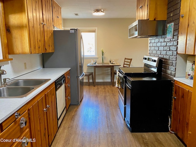 kitchen featuring stainless steel electric range, ventilation hood, white dishwasher, sink, and light wood-type flooring