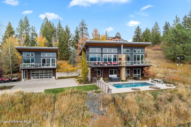 rear view of house with a garage, a swimming pool with hot tub, and a patio area