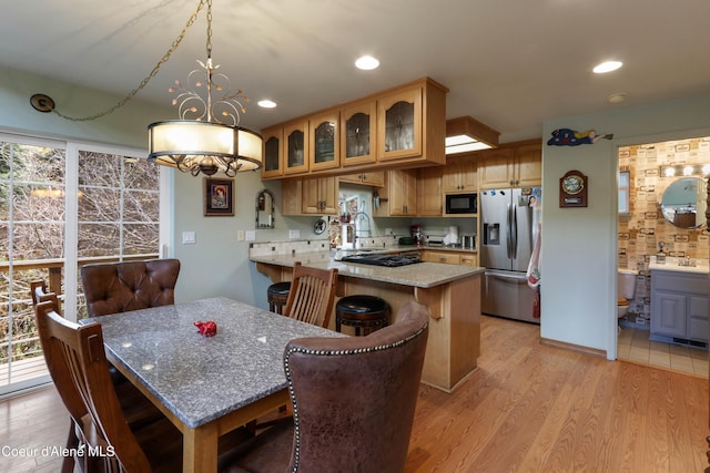 296 Ullr Dr, Sandpoint, ID 83864 - kitchen featuring a peninsula, glass insert cabinets, light wood-style floors, a sink, and black appliances