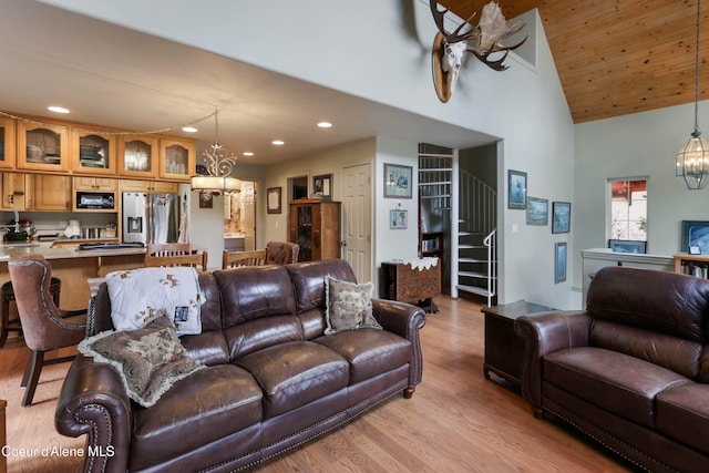 living room with light hardwood / wood-style floors, a notable chandelier, and high vaulted ceiling