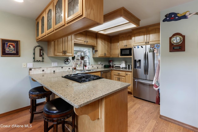 296 Ullr Dr, Sandpoint, ID 83864 - kitchen with a peninsula, a breakfast bar area, light wood-type flooring, a sink, and black appliances