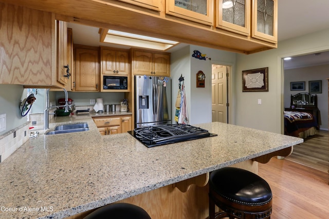 296 Ullr Dr, Sandpoint, ID 83864 - kitchen featuring a kitchen bar, a sink, light stone counters, black appliances, and light wood-style flooring