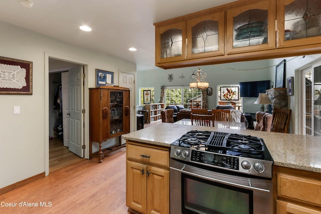 296 Ullr Dr, Sandpoint, ID 83864 - kitchen featuring light stone countertops, open floor plan, stainless steel gas range, recessed lighting, and light wood-style flooring