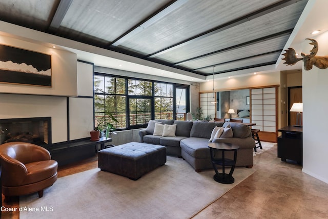 living area featuring recessed lighting, a fireplace with raised hearth, and concrete floors