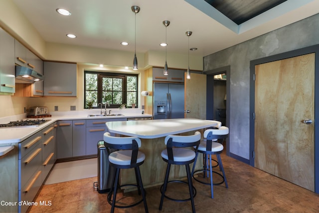 kitchen with a breakfast bar, decorative light fixtures, a kitchen island, sink, and appliances with stainless steel finishes