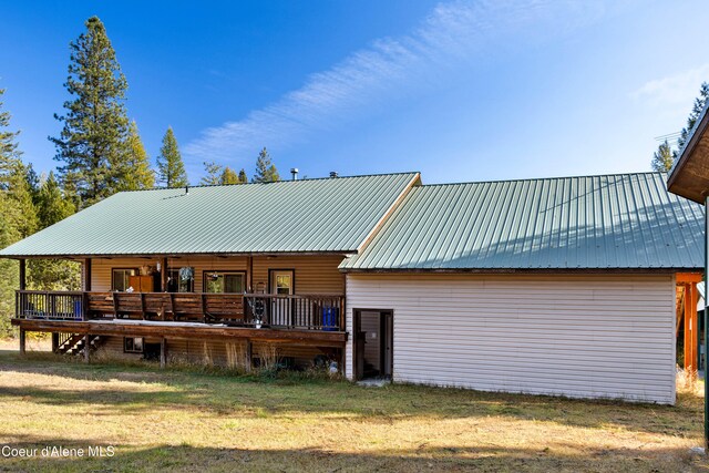 rear view of house with a wooden deck and a lawn