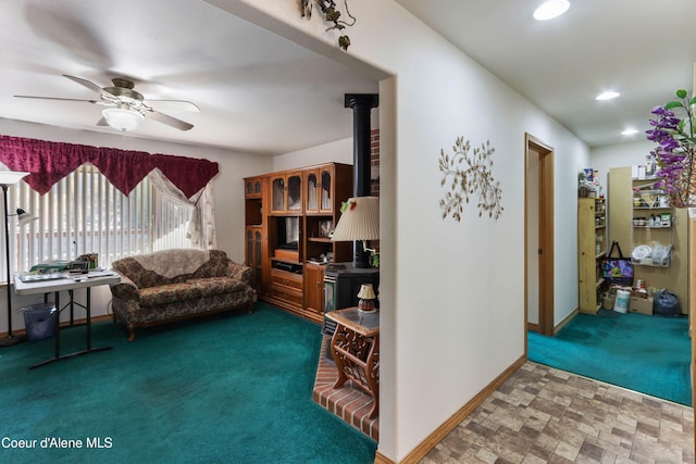 living room with carpet flooring, a wood stove, and ceiling fan