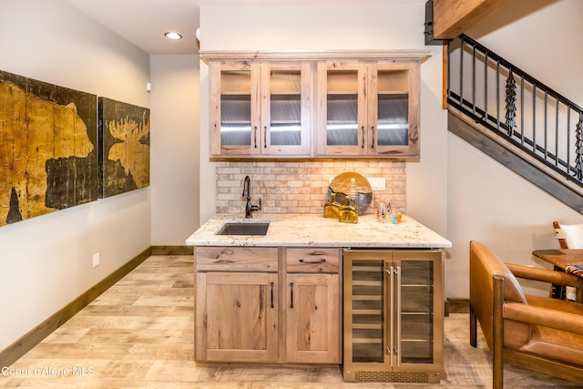 bar with wine cooler, light wood-type flooring, light stone countertops, decorative backsplash, and sink