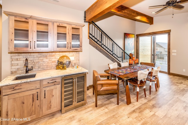 dining area featuring light hardwood / wood-style floors, ceiling fan, beam ceiling, wet bar, and wine cooler