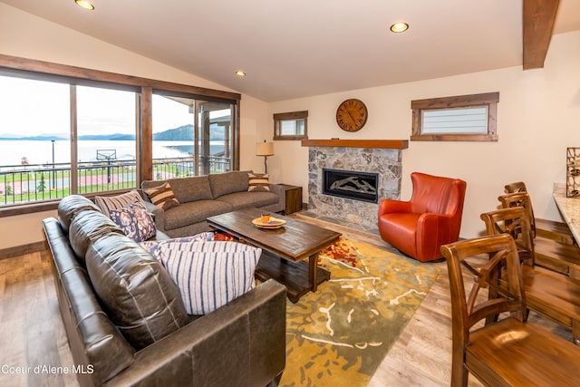 living room featuring hardwood / wood-style floors, a water view, lofted ceiling with beams, and a high end fireplace