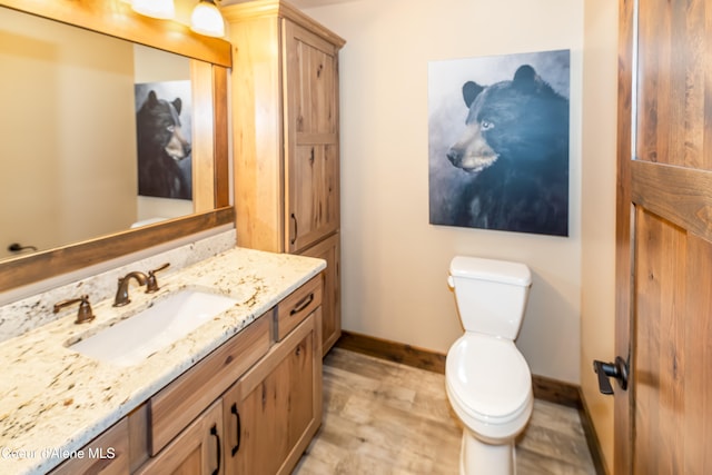 bathroom with hardwood / wood-style floors, vanity, and toilet