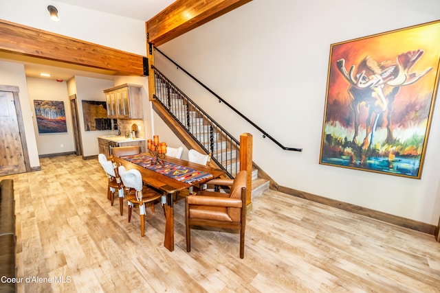 dining space featuring light hardwood / wood-style floors and beamed ceiling