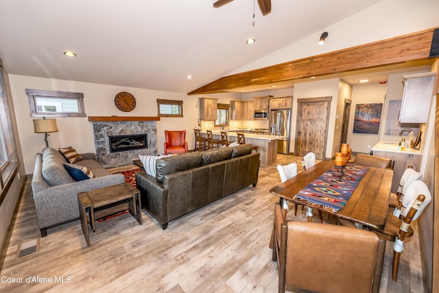 living room with light hardwood / wood-style floors, a high end fireplace, plenty of natural light, and lofted ceiling