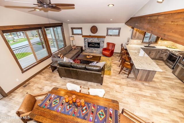 living room featuring sink, light wood-type flooring, vaulted ceiling, and ceiling fan