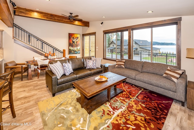 living room featuring light hardwood / wood-style flooring, a water view, vaulted ceiling with beams, and ceiling fan