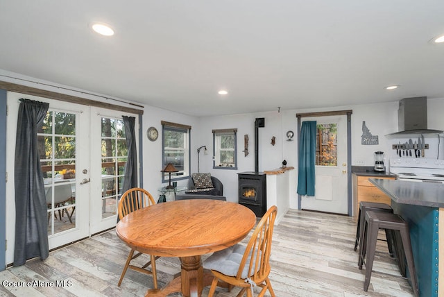 dining room featuring light hardwood / wood-style flooring, a wood stove, and french doors