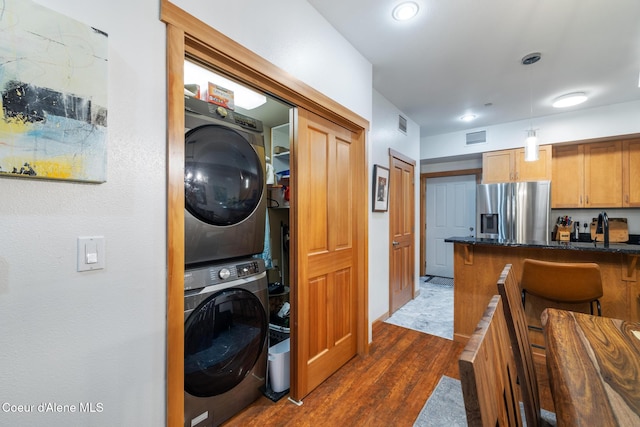 washroom featuring dark wood-type flooring and stacked washing maching and dryer