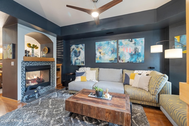 living room featuring hardwood / wood-style floors, ceiling fan, and a fireplace