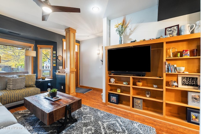 living room with decorative columns, wood-type flooring, and ceiling fan