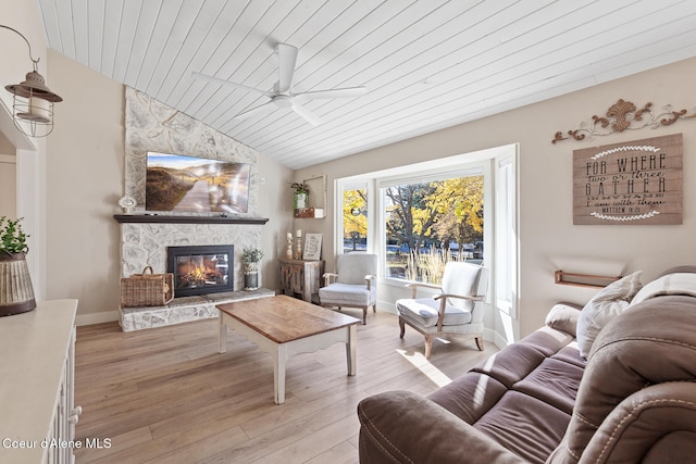 living room featuring wood ceiling, vaulted ceiling, light wood-type flooring, a fireplace, and ceiling fan