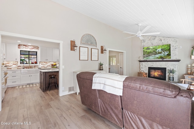 living room with a large fireplace, wood ceiling, light hardwood / wood-style floors, ceiling fan, and lofted ceiling