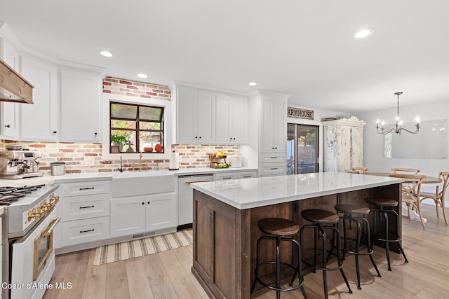 kitchen featuring high end stove, dishwasher, light hardwood / wood-style flooring, a center island, and white cabinets