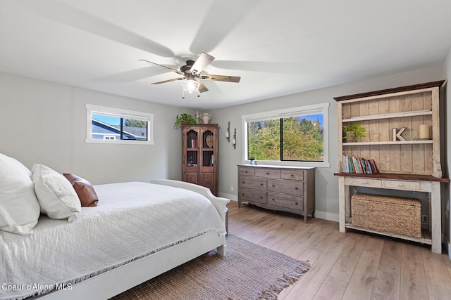 bedroom featuring ceiling fan, multiple windows, and light wood-type flooring