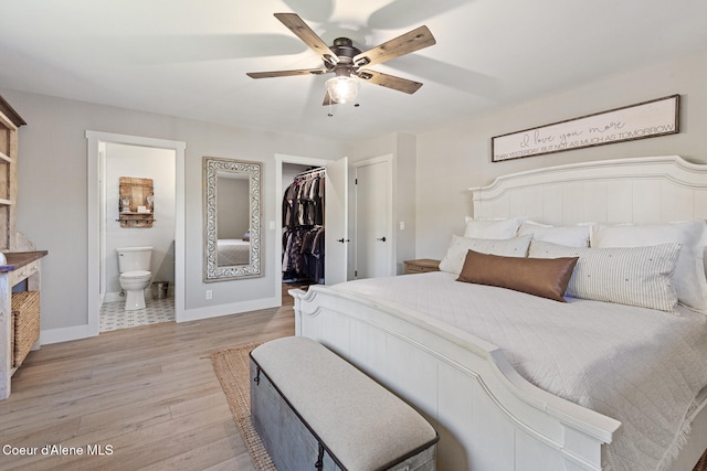 bedroom with a closet, a spacious closet, ensuite bathroom, light hardwood / wood-style floors, and ceiling fan