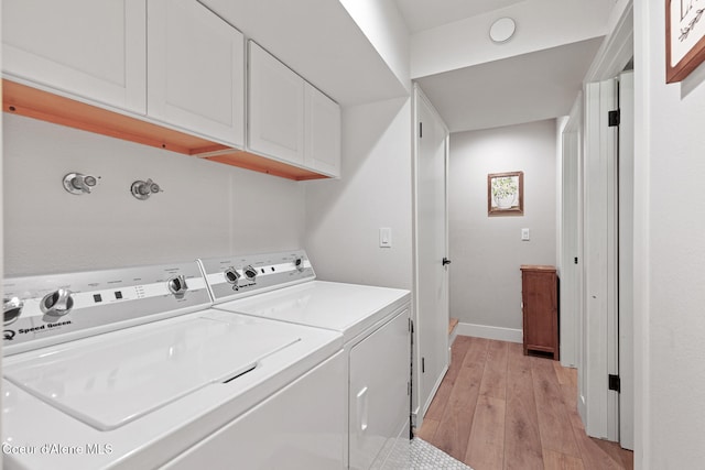 laundry area featuring cabinets, light hardwood / wood-style flooring, and washing machine and clothes dryer