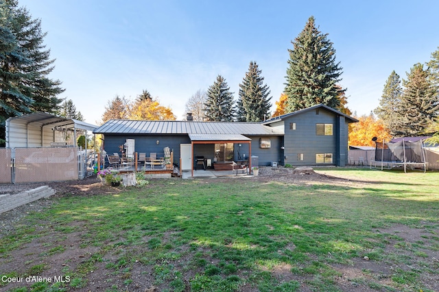 back of property featuring a patio area, a trampoline, and a lawn