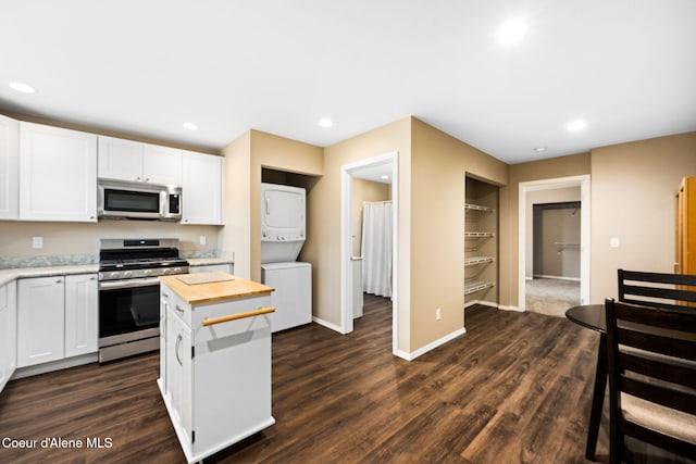 kitchen with stacked washer / dryer, dark wood-type flooring, appliances with stainless steel finishes, and white cabinets