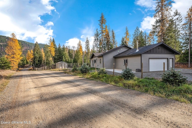 648 Curley Creek Rd, Moyie Springs, ID 83845 - view of side of property with an attached garage, board and batten siding, driveway, fence, and a storage unit