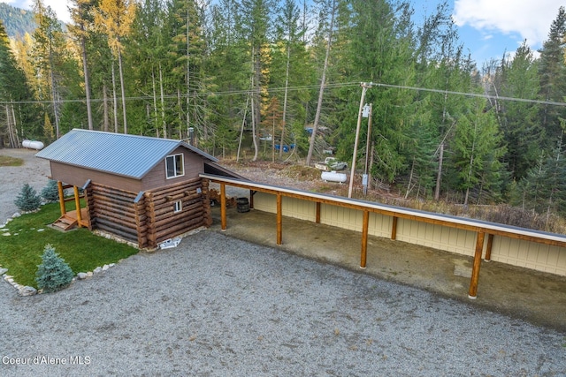 648 Curley Creek Rd, Moyie Springs, ID 83845 - view of front of home featuring log siding, a forest view, metal roof, a carport, and gravel driveway