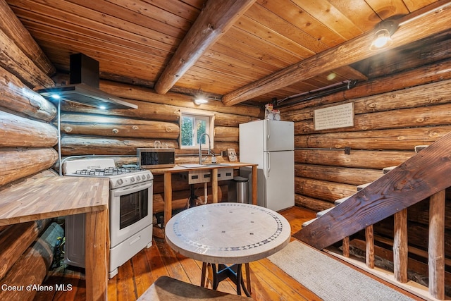 kitchen with extractor fan, beamed ceiling, hardwood / wood-style floors, rustic walls, and white appliances