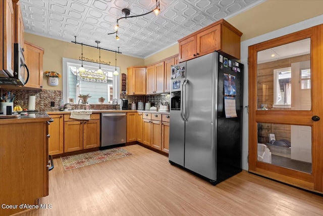 kitchen with stainless steel appliances, an ornate ceiling, light wood-style floors, decorative backsplash, and a sink