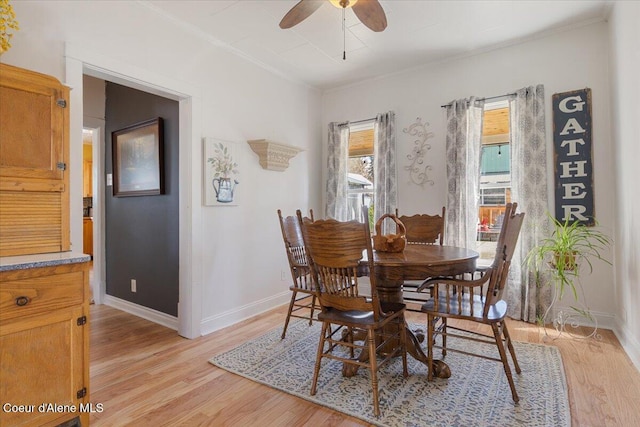 dining area featuring light wood finished floors, ornamental molding, a ceiling fan, and baseboards