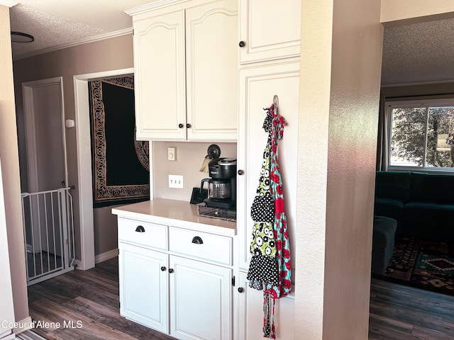 kitchen with a textured ceiling, ornamental molding, dark hardwood / wood-style flooring, and white cabinets