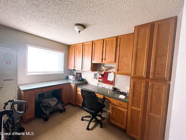 office area with light colored carpet, a textured ceiling, and built in desk