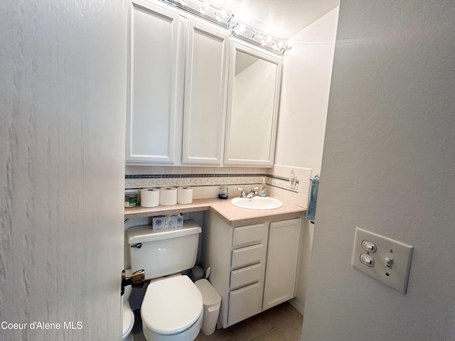 bathroom featuring backsplash, vanity, toilet, and tile patterned flooring