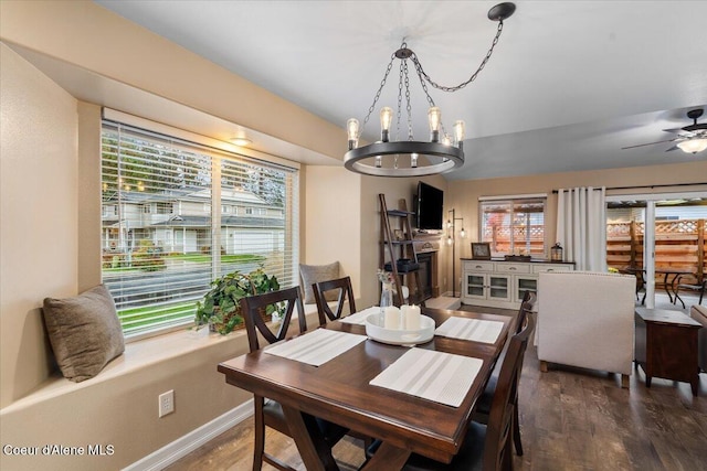 dining space featuring dark wood-type flooring, a healthy amount of sunlight, and ceiling fan with notable chandelier